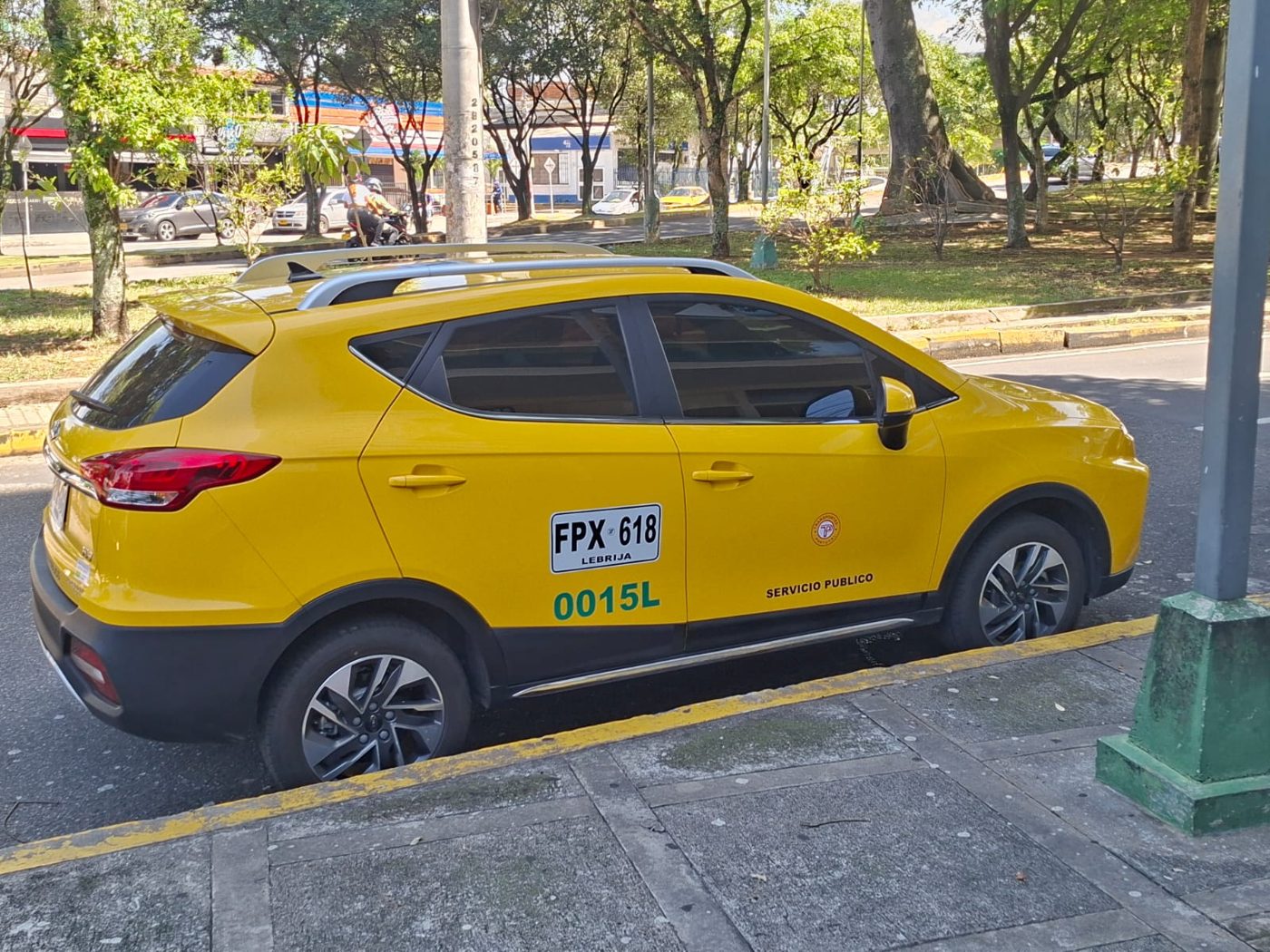 Vista trasera del taxi amarillo, placa FPX618, móvil 0015L